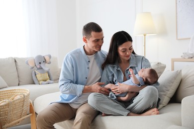 Photo of Happy family with cute baby on sofa at home