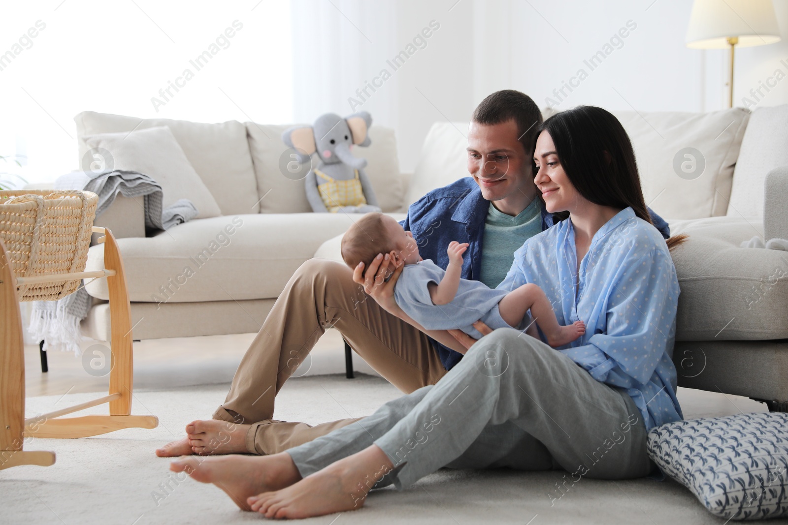 Photo of Happy family with cute baby near sofa at home