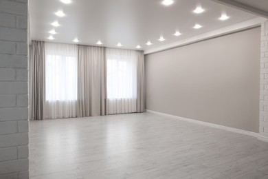 Photo of Empty room with beige wall, large window and wooden floor