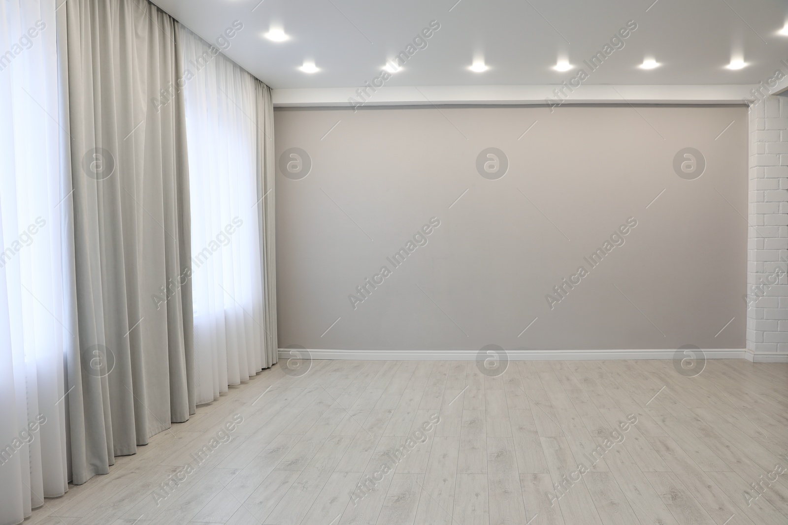 Empty room with beige wall, large window and wooden floor Photo of Empty room with beige wall, large window and wooden floor