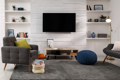 Photo of Cozy room interior with stylish furniture, decor and modern TV set
