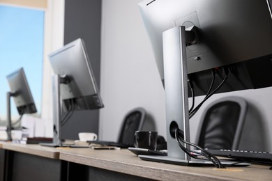 Photo of Open office interior. Modern workplaces with computers near light grey wall