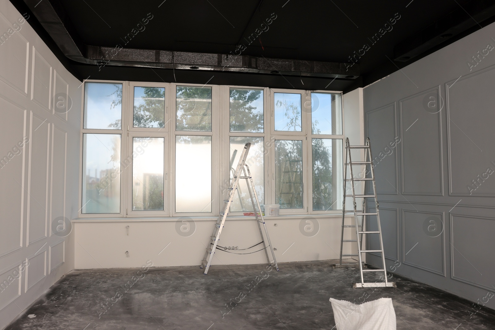 Photo of Metal ladders in empty room prepared for renovation