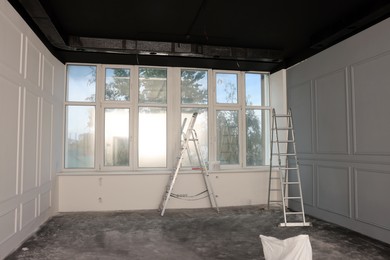 Photo of Metal ladders in empty room prepared for renovation
