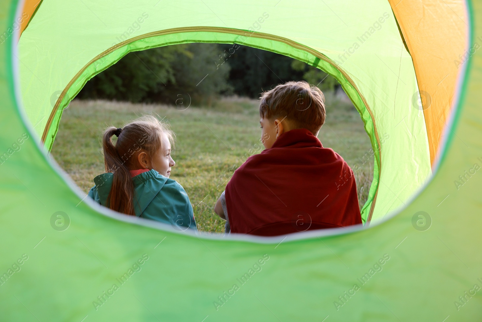 Photo of Brother and sister in camping tent, view from outside