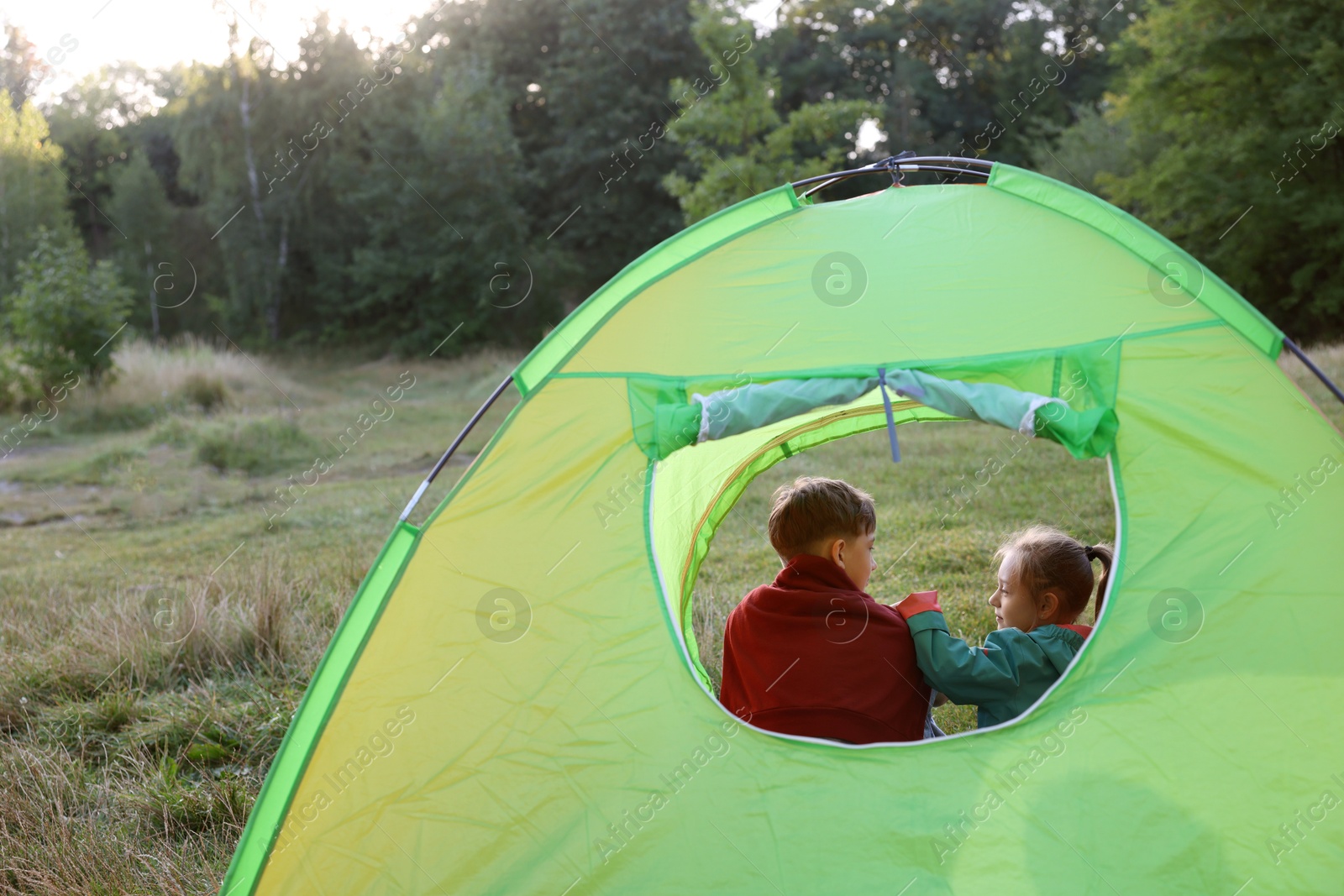 Photo of Brother and sister in camping tent, view from outside