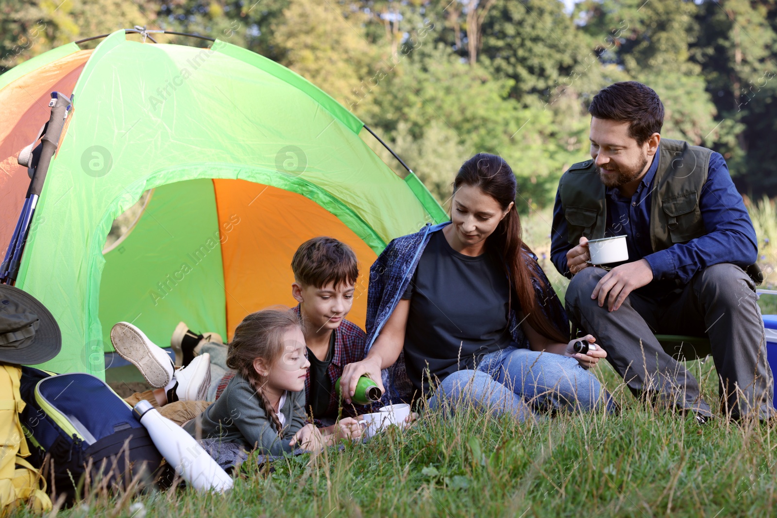 Photo of Family spending time together with camping tent and mugs of hot drink outdoors