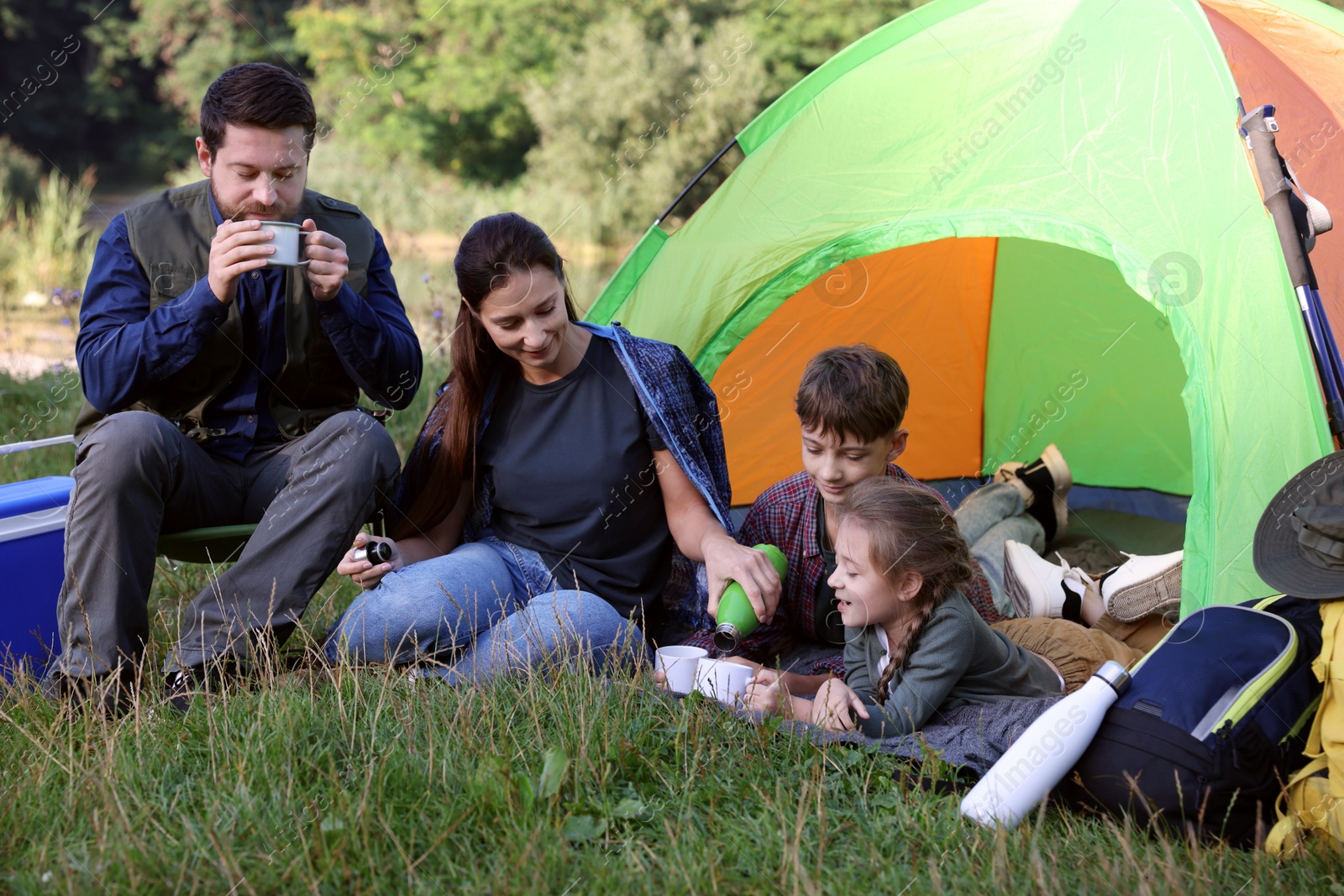 Photo of Family spending time together with camping tent and mugs of hot drink outdoors