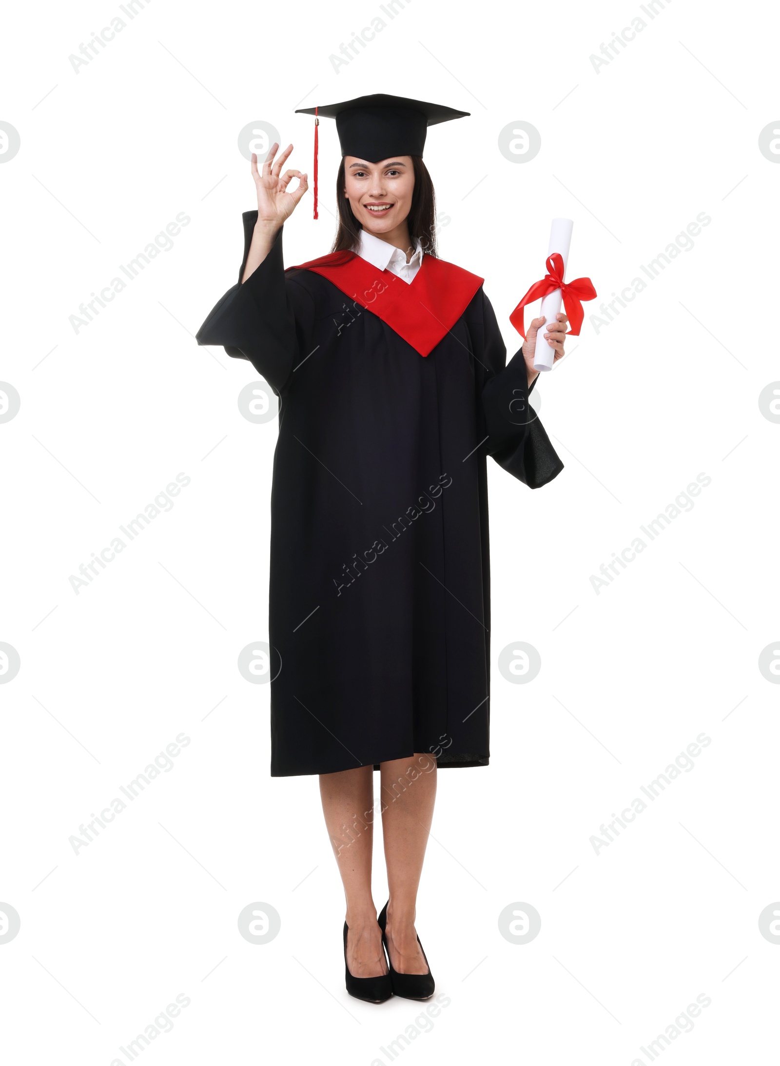 Photo of Happy young woman in graduation gown and mortarboard with diploma showing ok gesture on white background