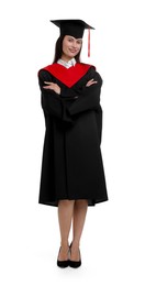 Photo of Happy young woman in graduation gown and mortarboard on white background