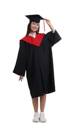 Photo of Happy young woman in graduation gown and mortarboard on white background