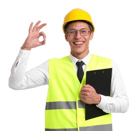 Photo of Portrait of engineer in hard hat and reflective vest with clipboard showing ok gesture on white background