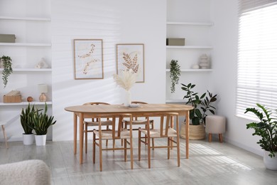 Photo of Stylish wooden table with chairs and decor indoors. Interior design