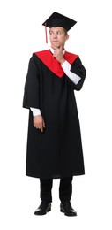 Photo of Thoughtful young man in graduation gown and mortarboard on white background