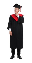 Photo of Thoughtful young man in graduation gown and mortarboard on white background