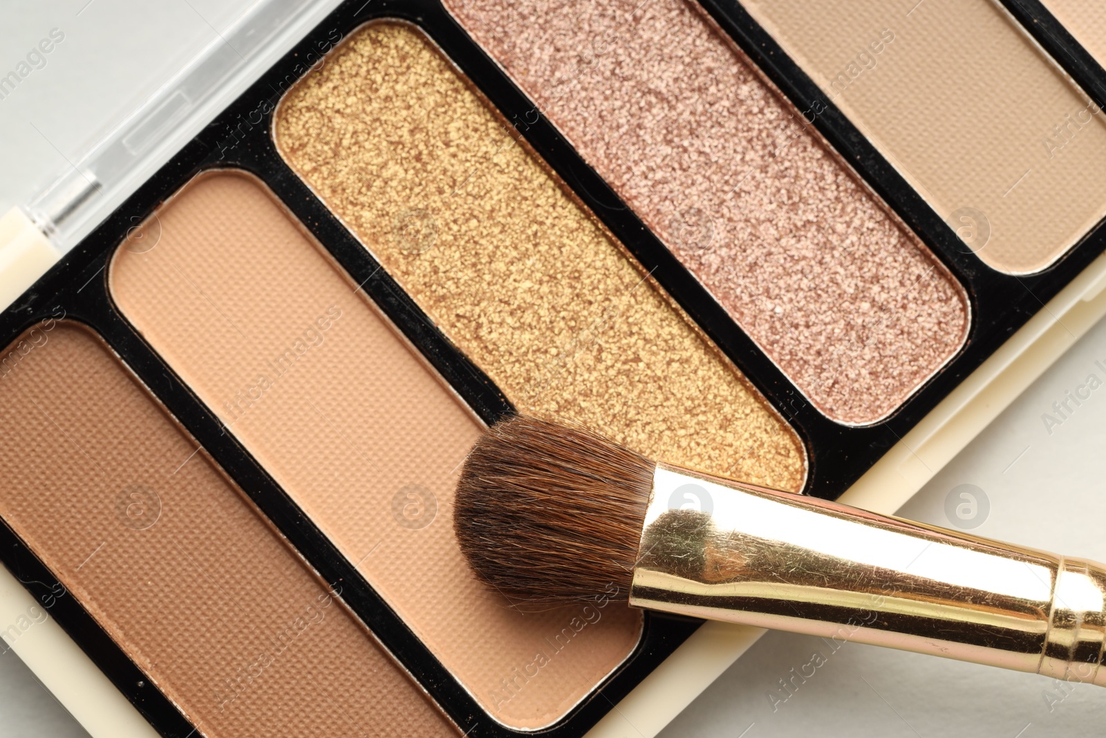 Photo of Beautiful eyeshadow palette and brush on white table, top view