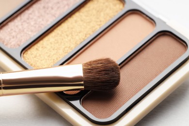 Photo of Beautiful eyeshadow palette and brush on white table, closeup
