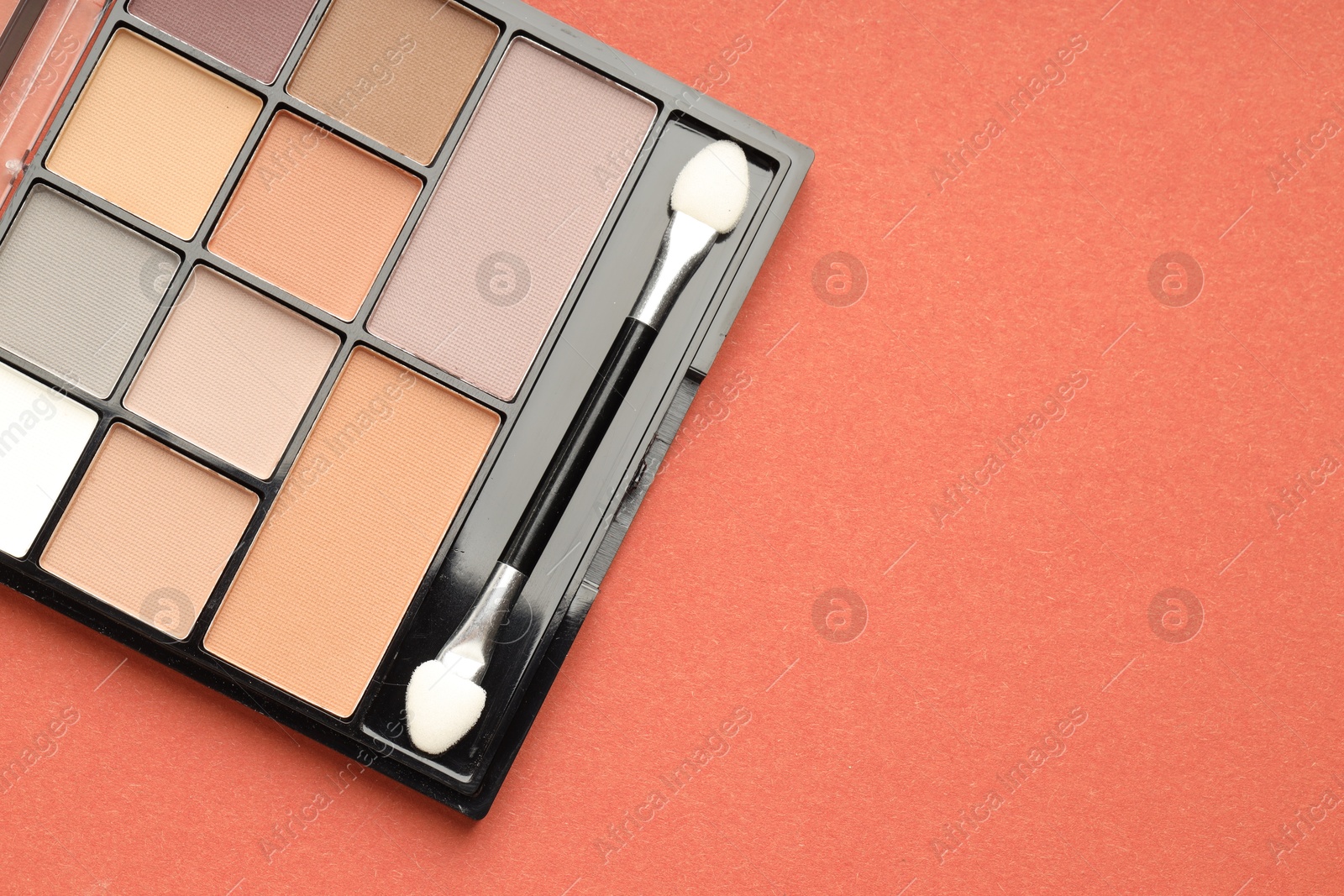 Photo of Beautiful eyeshadow palette and brush on coral background, top view. Space for text
