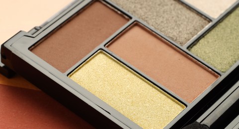 Photo of Beautiful eyeshadow palette on coral background, closeup