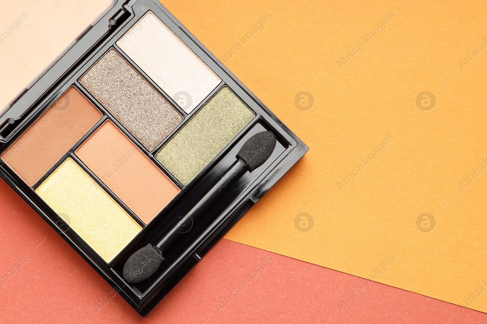 Beautiful eyeshadow palette and brush on color background, top view. Space for text Photo of Beautiful eyeshadow palette and brush on color background, top view. Space for text