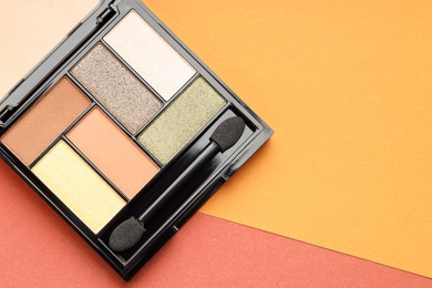 Photo of Beautiful eyeshadow palette and brush on color background, top view. Space for text