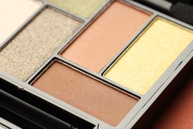 Photo of Beautiful eyeshadow palette on coral background, closeup
