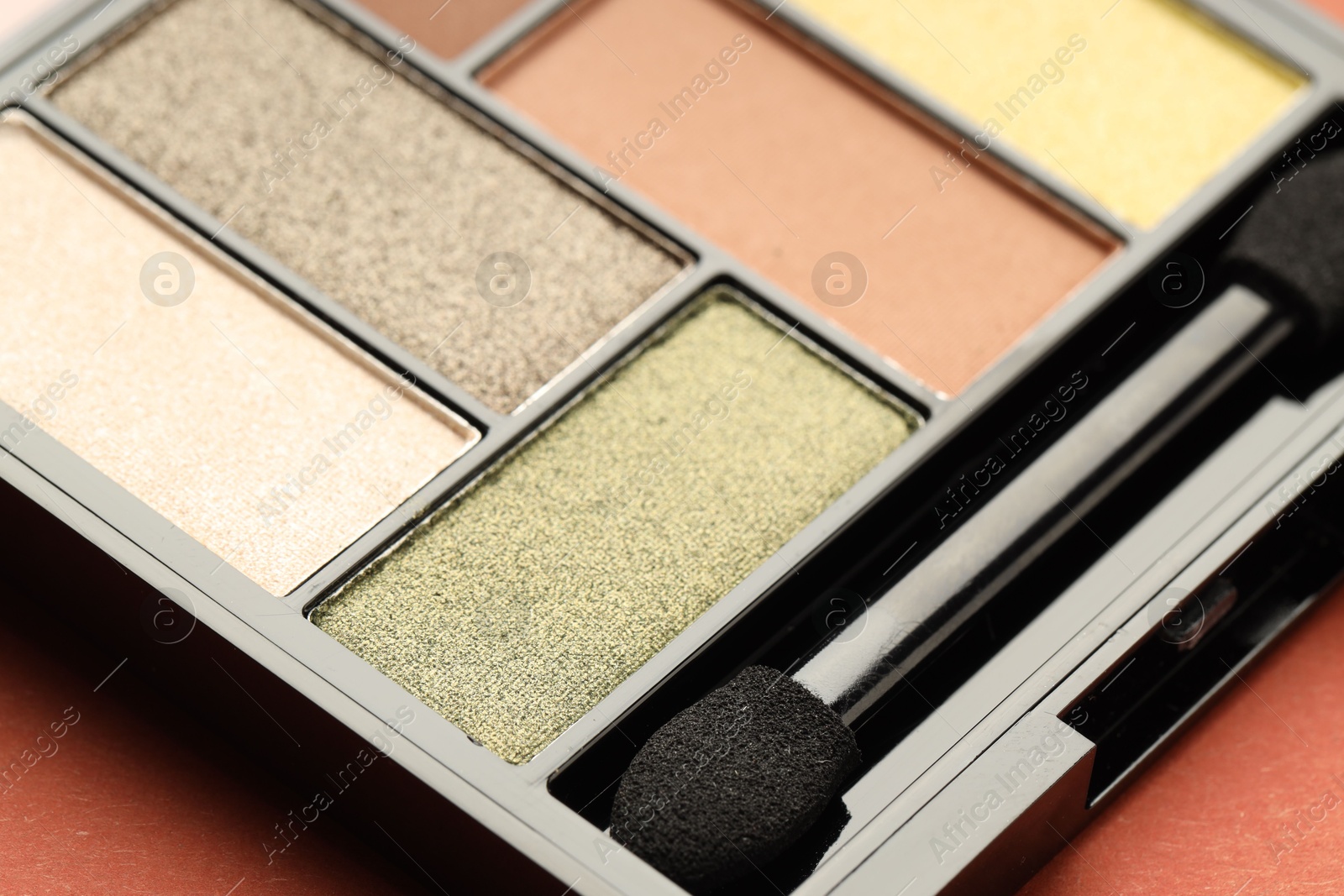 Photo of Beautiful eyeshadow palette and brush on coral background, closeup