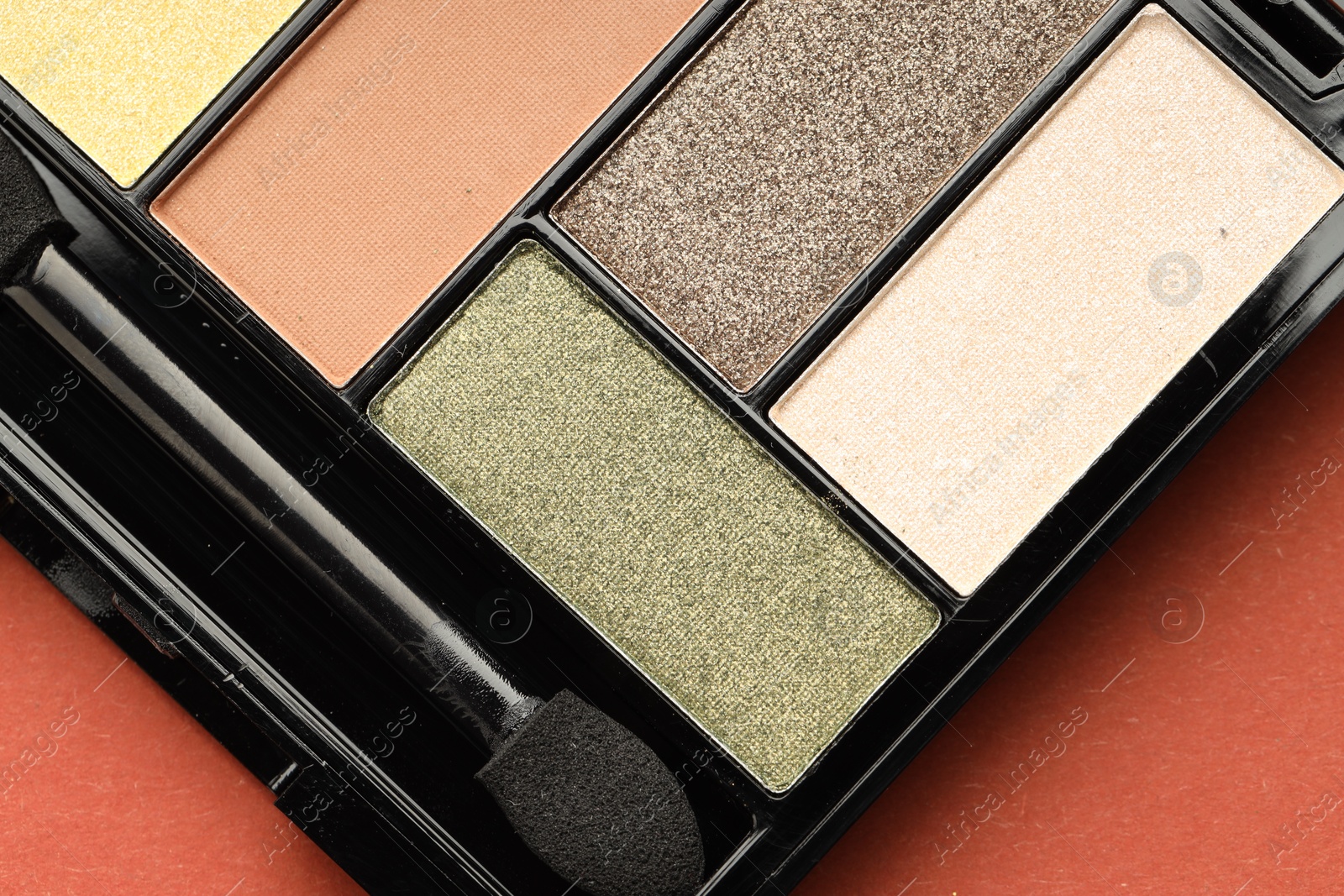 Beautiful eyeshadow palette and brush on coral background, top view Photo of Beautiful eyeshadow palette and brush on coral background, top view