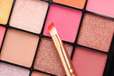 Photo of Beautiful eyeshadow palette and brush as background, top view