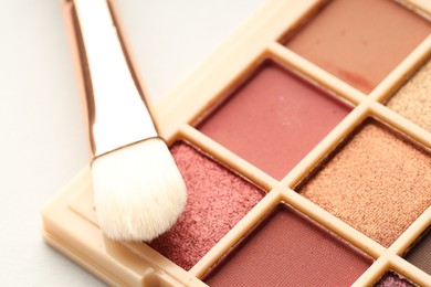 Photo of Beautiful eyeshadow palette and brush on white background, closeup