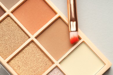 Photo of Beautiful eyeshadow palette and brush on white background, top view