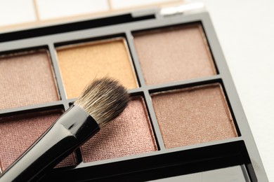 Photo of Beautiful eyeshadow palette and brush on white background, closeup