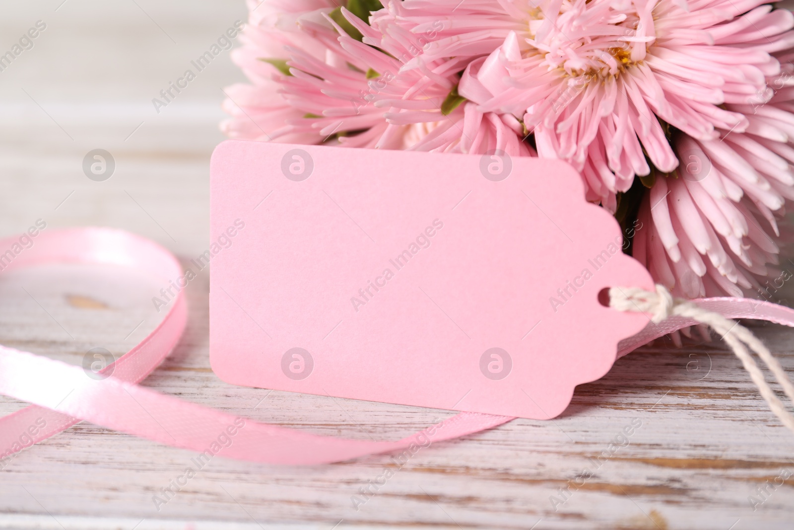 Blank card and flowers on white wooden desk, closeup. Space for text Photo of Blank card and flowers on white wooden desk, closeup. Space for text