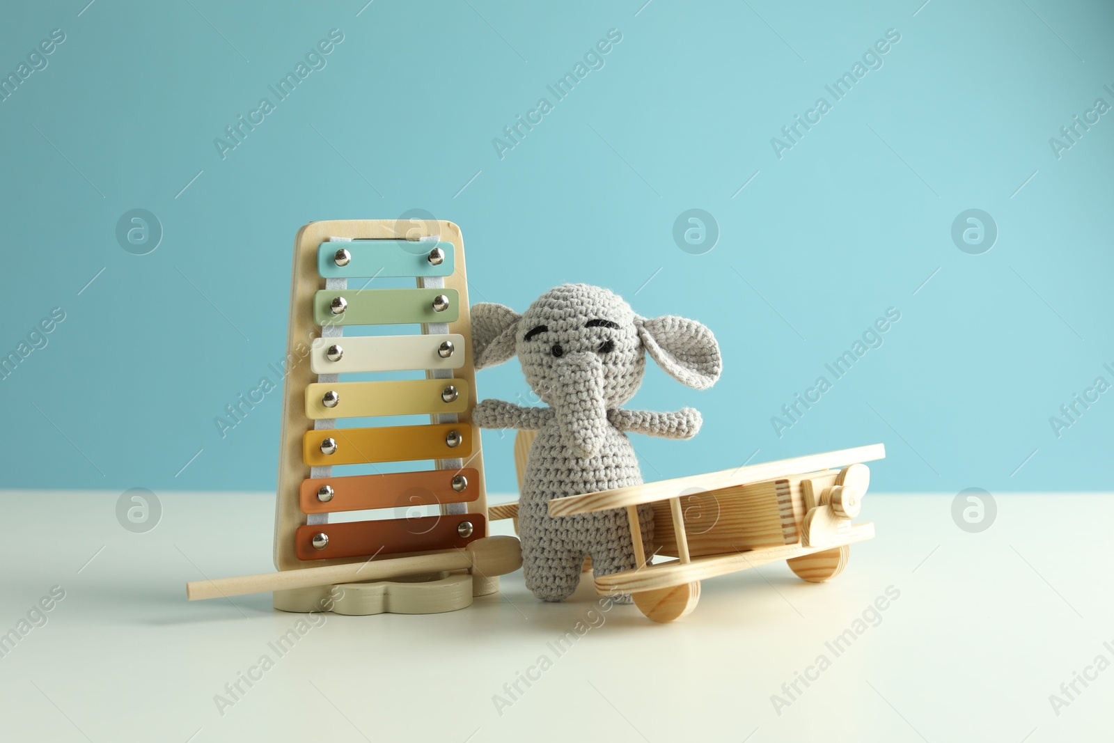 Different cute toys on white table against light blue background Photo of Different cute toys on white table against light blue background