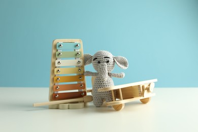 Photo of Different cute toys on white table against light blue background