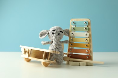 Photo of Different cute toys on white table against light blue background