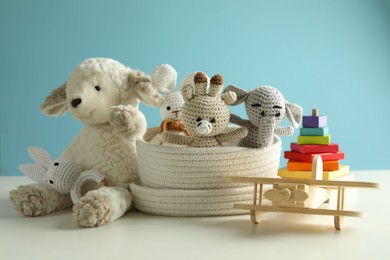 Photo of Different cute toys on white table against light blue background