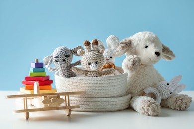 Photo of Different cute toys on white table against light blue background