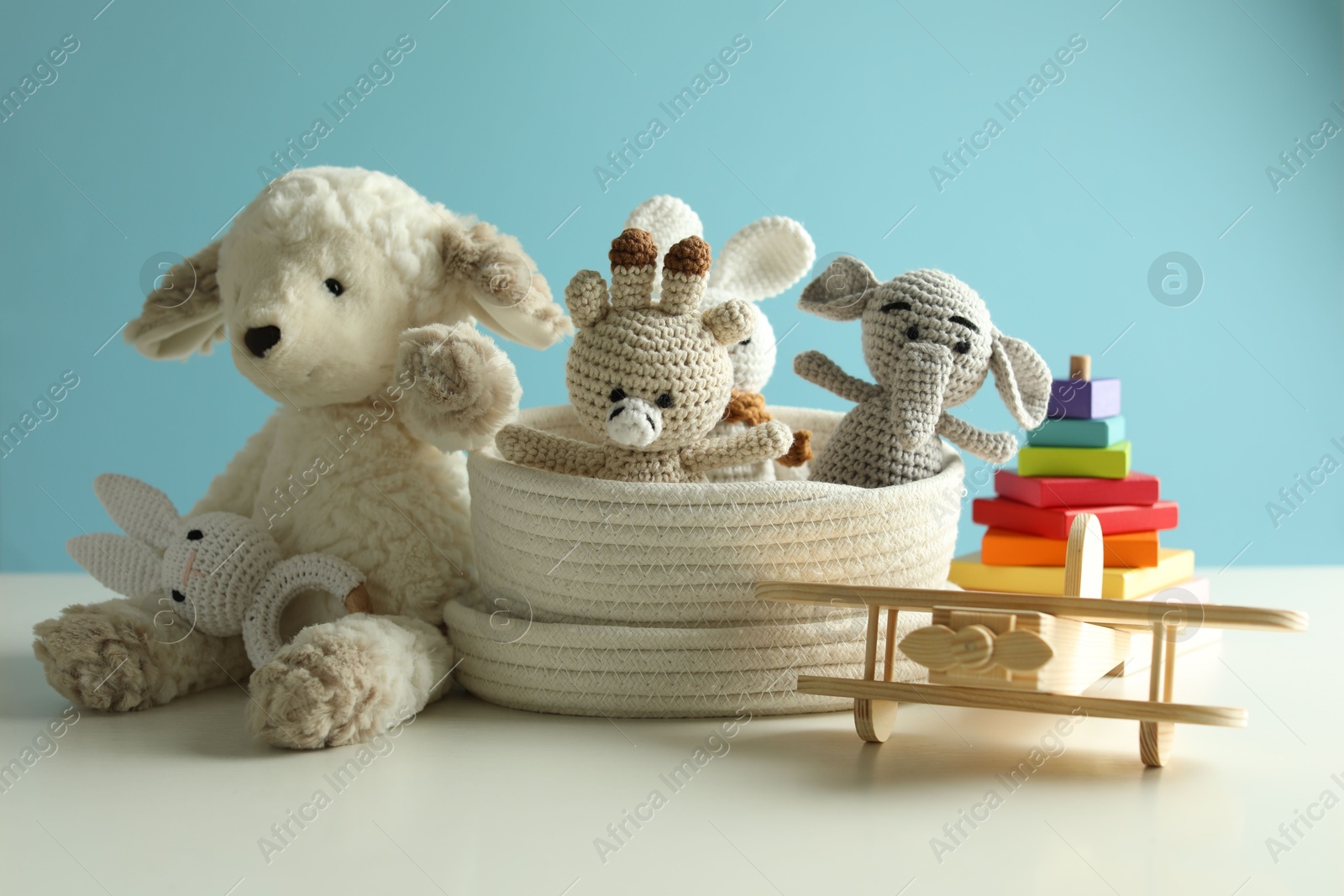 Different cute toys on white table against light blue background Photo of Different cute toys on white table against light blue background