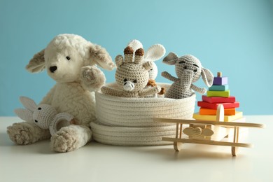 Photo of Different cute toys on white table against light blue background