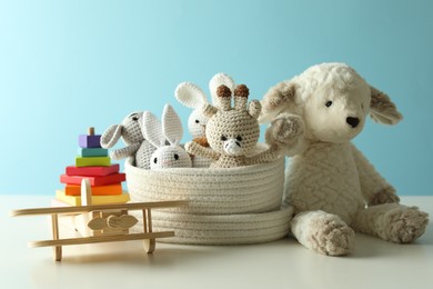 Photo of Different cute toys on white table against light blue background
