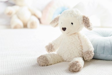 Photo of Cute soft toy sheep on bed, closeup. Space for text