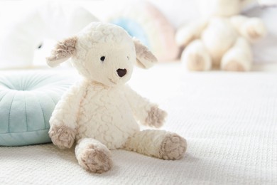 Photo of Cute soft toy sheep on bed, closeup. Space for text
