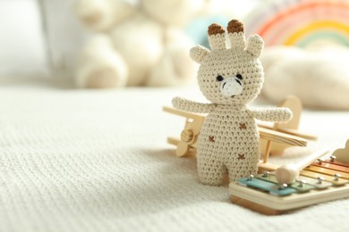 Photo of Cute giraffe, airplane and xylophone toys on bed, closeup. Space for text