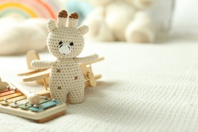 Photo of Cute giraffe, airplane and xylophone toys on bed, closeup. Space for text