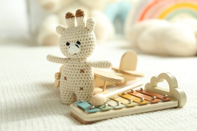 Photo of Cute giraffe, airplane and xylophone toys on bed, closeup