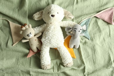 Photo of Cute soft toys and garland on olive fabric, top view