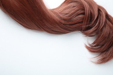 Photo of Auburn hair strand on white background, top view. Space for text