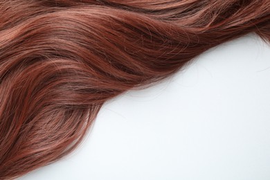 Photo of Auburn hair strand on white background, top view. Space for text