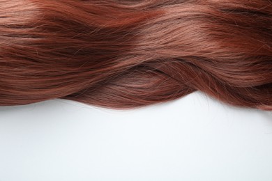 Photo of Auburn hair strand on white background, top view. Space for text